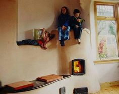 two children are sitting on the edge of a wall with wood burning stoves in it