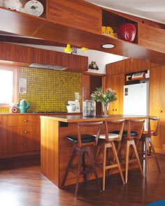 a kitchen with wooden cabinets and chairs in the center island, next to a dining room table