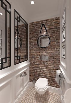 a white toilet sitting in a bathroom next to a brick wall with pictures on it