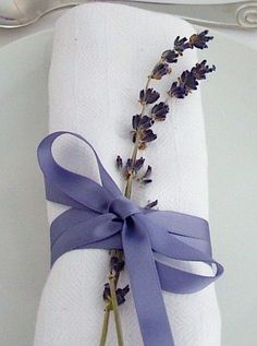 a white plate topped with a purple ribbon and lavender sprig on top of a napkin