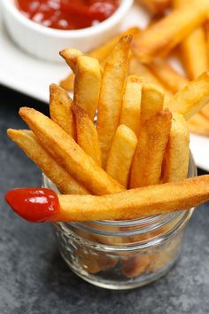 french fries with ketchup in a small glass container