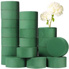 a white flower sitting on top of stacks of green tape next to some round containers