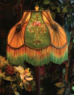 a lamp that is sitting on top of a wooden stand in front of some flowers