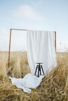 an empty chair in the middle of a field with a white sheet draped over it