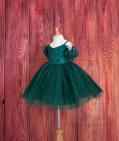 Little Darln Boutique  Our enchanting Knee Length flower girl dresses are sure to turn heads! This beautiful elegant dress is handmade, the bodice consists of Hunter Green satin with a layer of pearl tulle, followed by spaghetti straps and of the shoulder tulle sleeves. The back of the dress has a zipper for closure. The skirt consists of 4 Hunter Green layers of tulle with the top layer consisting of pearl beads. The fifth layer is made of lining with crinoline for fullness.  This dress is perfect for any occasion!  Dress Is Pictured with a petticoat NOT INCLUDED https://www.etsy.com/listing/1316417982/white-knee-length-petticoat-wedding?click_key=41cb8b0ae4587efa582b0a433f3f5e0cde12aec0%3A1316417982&click_sum=af1df37b&ref=shop_home_active_1 Visit our store, more items to come!  https://w Elegant Green Tutu Dress For Pageant, Green Christmas Pageant Dress, Elegant Green Pageant Dress For Dress-up, Elegant Christmas Pageant Gown, Fitted Tulle Holiday Dress For Pageant, Fitted Tulle Holiday Dress For Pageants, Elegant Holiday Dress With Tulle For Pageants, Christmas Princess Tulle Pageant Dress, Fitted Holiday Tutu Dress For Pageant