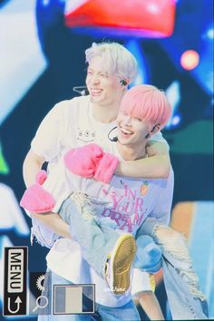 two people hugging each other on stage with one person wearing pink gloves and the other holding a stuffed animal