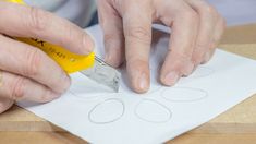 a person cutting out circles with a pair of scissors on top of a piece of paper