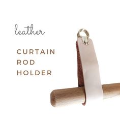 the leather curtain rod holder is made out of wood and has a white ribbon hanging from it