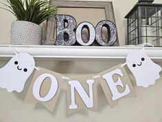 a ghost banner hanging on the mantle in front of a sign that reads boo one