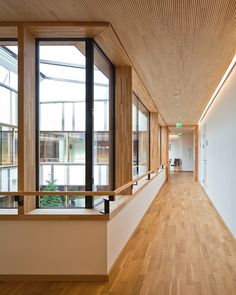 an empty hallway with wooden floors and large windows on both sides, leading to the second floor