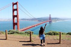 a woman is pointing at the golden gate bridge