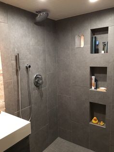 a walk in shower sitting next to a white sink and counter top under a faucet