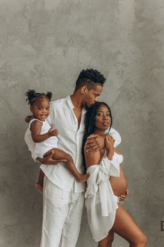 a man, woman and child posing for a photo in white outfits with their arms around each other