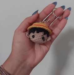 a hand holding a tiny crocheted doll with a hat on it's head