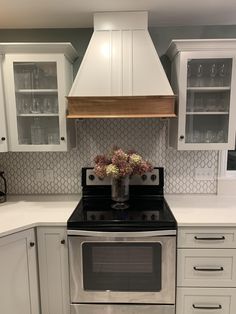 a stove top oven sitting inside of a kitchen next to white cabinets and counter tops