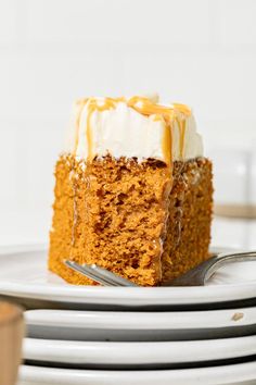 a slice of carrot cake sitting on top of white plates with silverware next to it