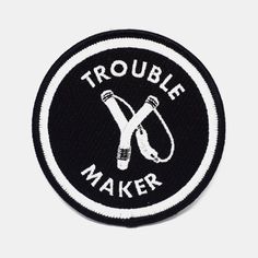 a black and white circular patch with the words trouble maker written in white on it