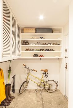 a bike is parked in the corner of a room next to some shoes and umbrellas