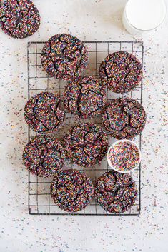 sprinkle covered donuts sitting on a cooling rack