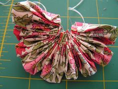 a close up of a paper flower on a cutting board with scissors and thread attached to it