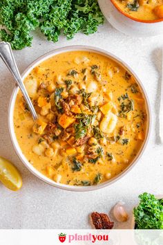 two bowls filled with soup next to lemon wedges and kale on the side