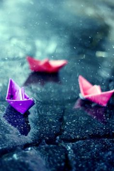 three origami boats floating in the rain