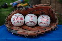 three baseballs sitting in a catchers mitt on a blue cloth covered table