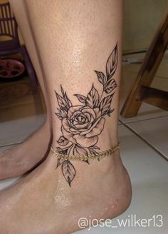 a woman's foot with a rose and leaves tattoo on the side of her leg