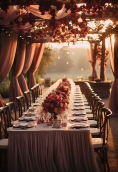 a long table is set with place settings and flowers on it for an elegant dinner