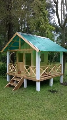 a small wooden cabin in the middle of a grassy area with stairs leading up to it