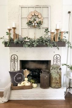 a fireplace with candles, pumpkins and greenery on the mantel above it