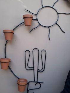 four potted plants are arranged in the shape of a sun on a white wall