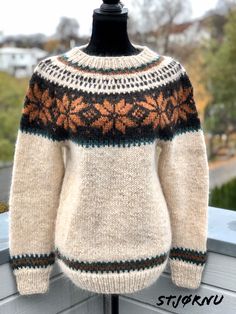 a white sweater with an orange and black design on the front is sitting on a mannequin