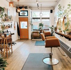 a salon with lots of chairs and plants on the wall, in front of an open door