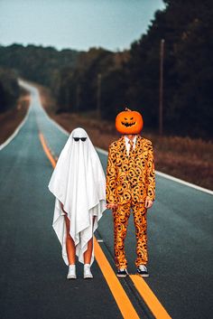 two people in halloween costumes are standing on the road