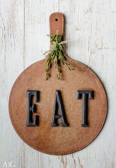 a wooden sign with the word eat hanging from it's side on a wall