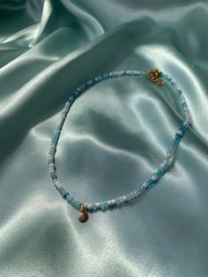 seed beaded blue necklace with a seashell charm. The whole length of the necklace (including extension) is 45cm. If you have any questions, please message me! Blue Beaded Charm Necklaces With Round Beads, Blue Strand Necklace With Tiny Beads, Dainty Handmade Blue Beaded Necklace, Blue Beaded Dainty Necklace, Handmade Ocean-inspired Gold Beaded Necklaces, Dainty Blue Beaded Necklace, Ocean-inspired Blue Beaded Necklace With Colorful Beads, Ocean-inspired Colorful Beaded Necklace As Gift, Ocean-inspired Colorful Beaded Necklace For Gift