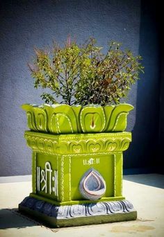 a green planter sitting on top of a cement slab next to a building wall