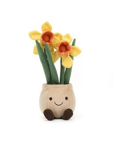 a small vase filled with yellow flowers on top of a white table next to a stuffed animal