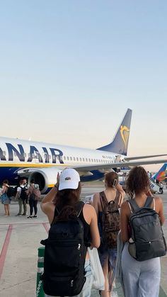 two women are standing in front of an airplane on the tarmac with their backs turned