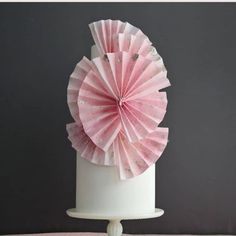 a pink paper fan sitting on top of a white cake with the words how to make wafer paper topper