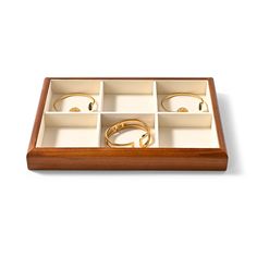 an open wooden box with six rings inside