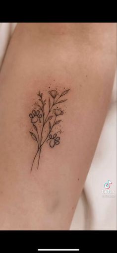 a small flower tattoo on the back of a woman's arm