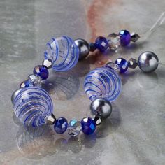 a bracelet made out of glass beads and silver balls on top of a marble surface