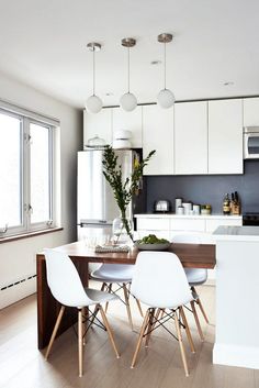 an image of a kitchen setting with white chairs and wooden table in the center area