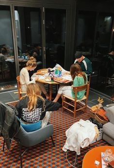 a group of people sitting around a table in a room with orange and white checkered flooring