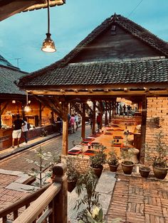 an outdoor dining area with potted plants and lights hanging from the roof over it