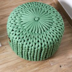 a green poufce sitting on top of a wooden floor