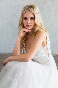 a woman in a white dress sitting on the floor with her hand under her chin