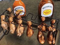 chicken wings are being cooked on a grill with honey and ketchup bottles in the background